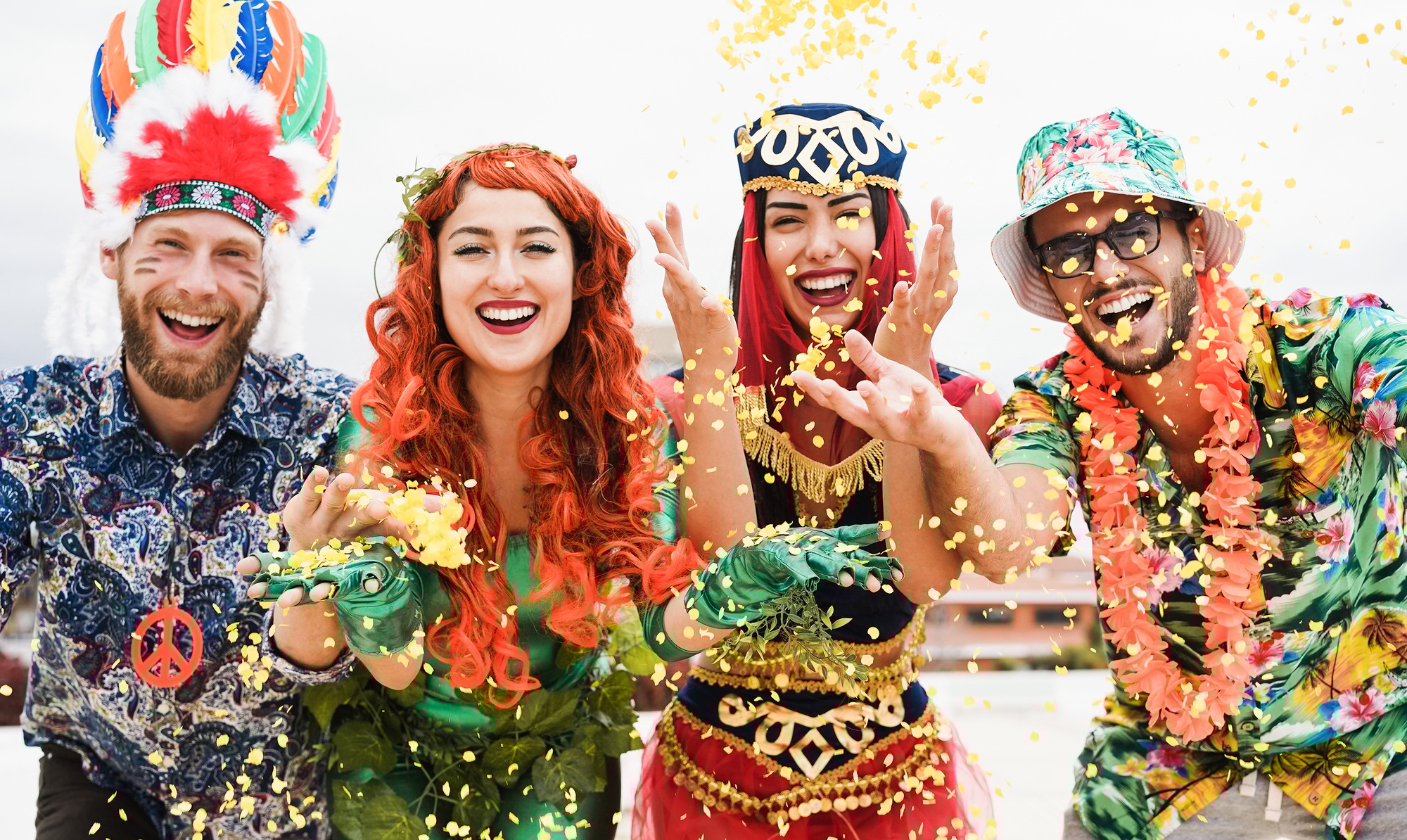 Happy dressed people celebrating at carnival party throwing confetti